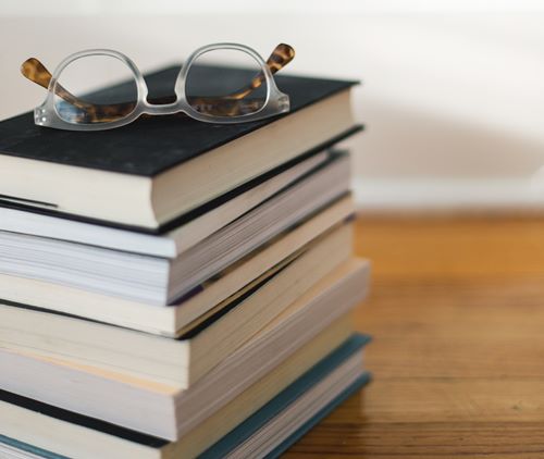 stack of books with reading glasses
